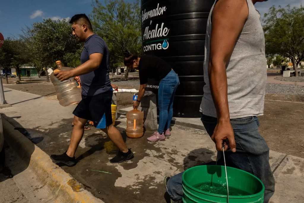 Personas llenando cubos de agua de una cisterna que el gobierno colocó para abastecer a los barrios de Ciénega de Flores, un pueblo cerca de Monterrey.